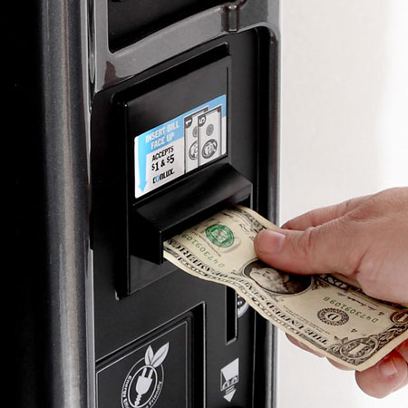 Customer purchasing a product from a vending machine with a $1 bill through the machine's bill acceptor.